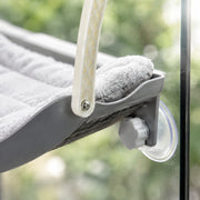 Close-up detail of the curved suction-cup window hammock — light gray
